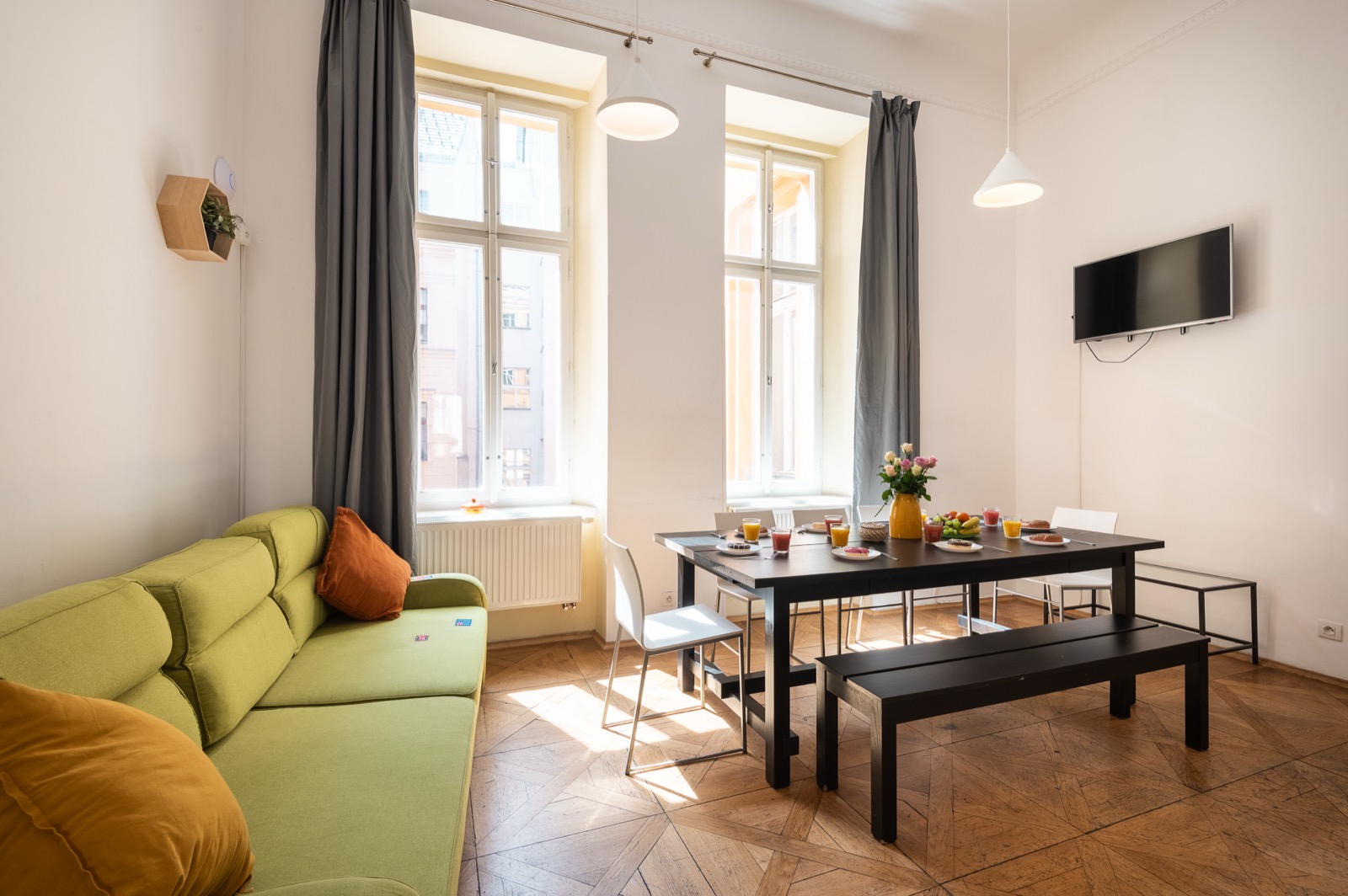 Apartmán H05 — obývací pokoj se zelenou pohovkou a parketami