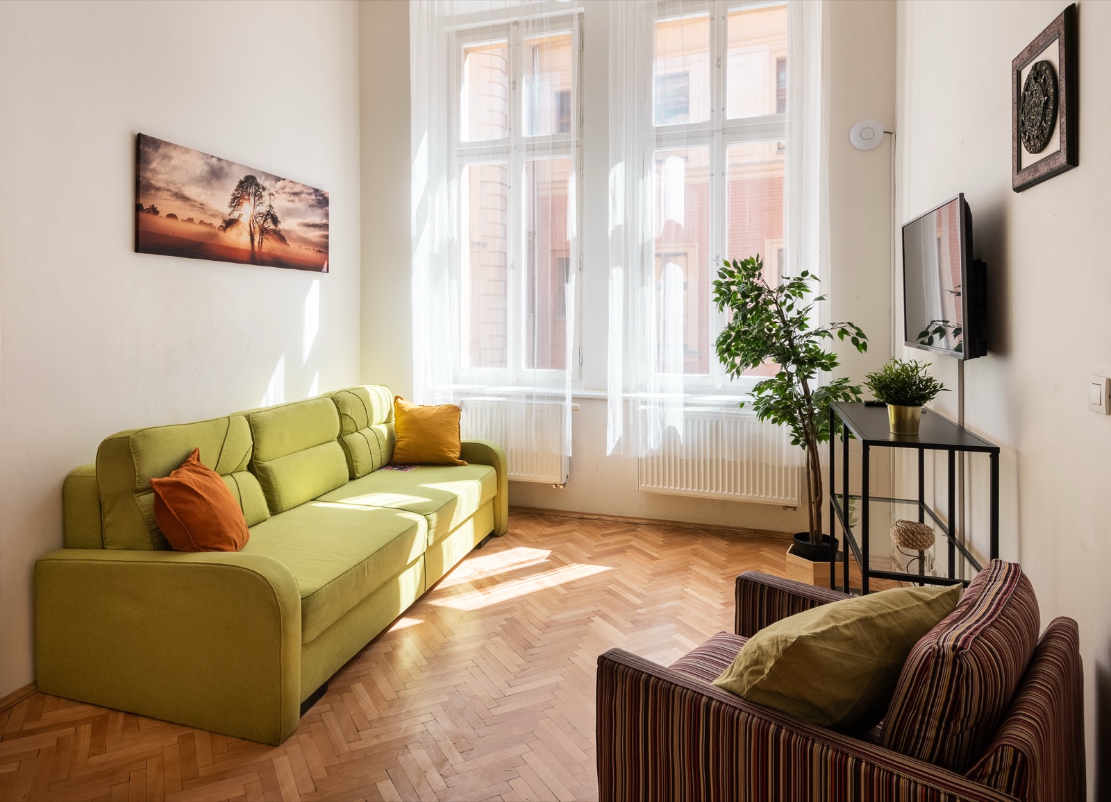 Apartmán H06 — prosluněný obývák se zeleným rohovým sedákem