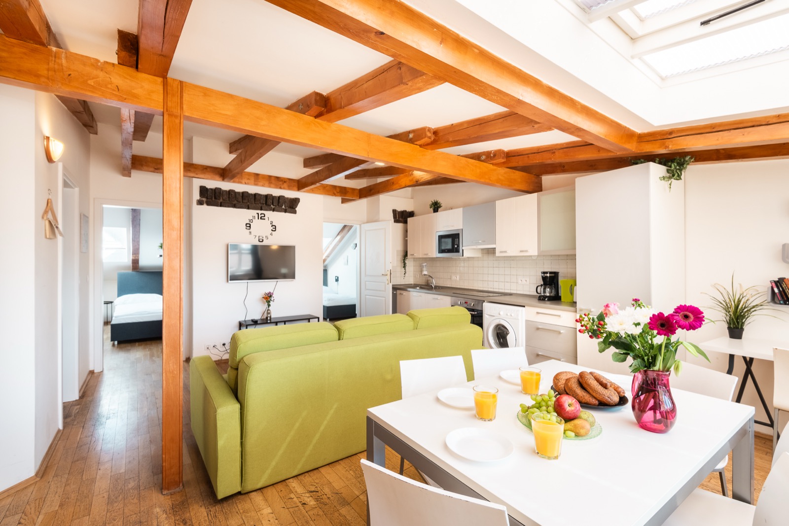 Apartmán H14 — podkrovní obývák s trámy a zelenou pohovkou